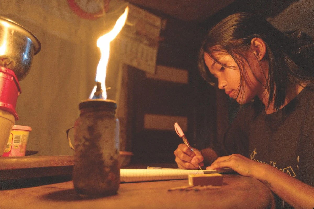 FROM GAS LAMPS TO ELECTRIC LIGHTS Young student Mitch Balbuena used to do her homework using a gas lamp for illumination up until the sitio electrification program brought by Davao Light finally reached their home.