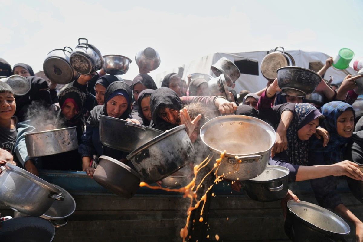 Palestinians struggle to get donated food at a community kitchen in Khan Younis, Gaza Strip, Monday, May 5, 2025. (AP Photo/Abdel Kareem Hana)