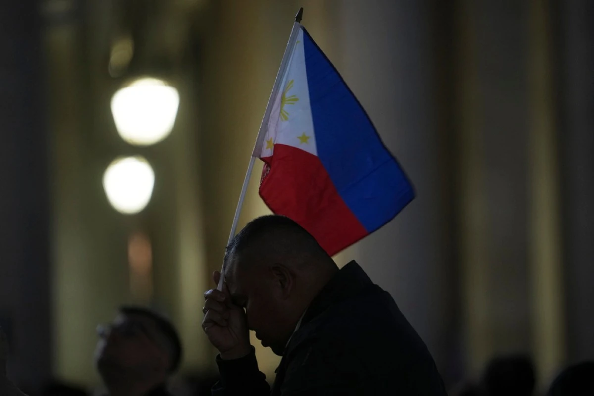 A pilgrim holds a flag of the Philippines in St Peter's Square during the cardinals' conclave to elect a new pope, at the Vatican, Wednesday, May 7, 2025. (AP Photo/Alessandra Tarantino)