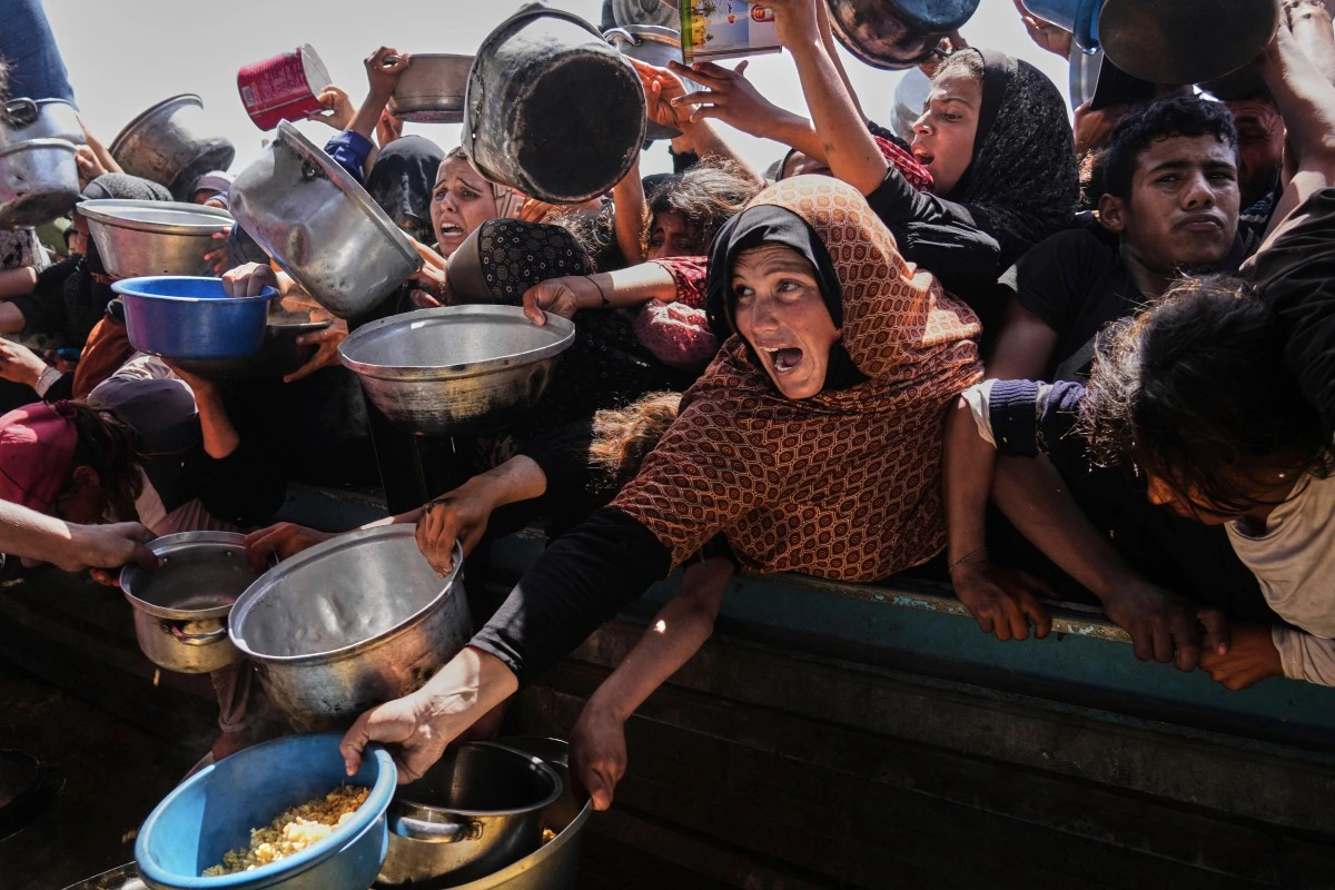 Palestinians struggle to obtain donated food at a community kitchen in Khan Younis, in the southern Gaza Strip, Friday, May 9, 2025. (AP Photo/Abdel Kareem Hana)