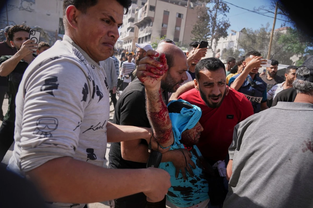 A man is carried away after being injured in an Israeli army drone strike on a sidewalk which killed at least two people, in downtown Gaza City, Friday, May 9, 2025. (AP Photo/Jehad Alshrafi)