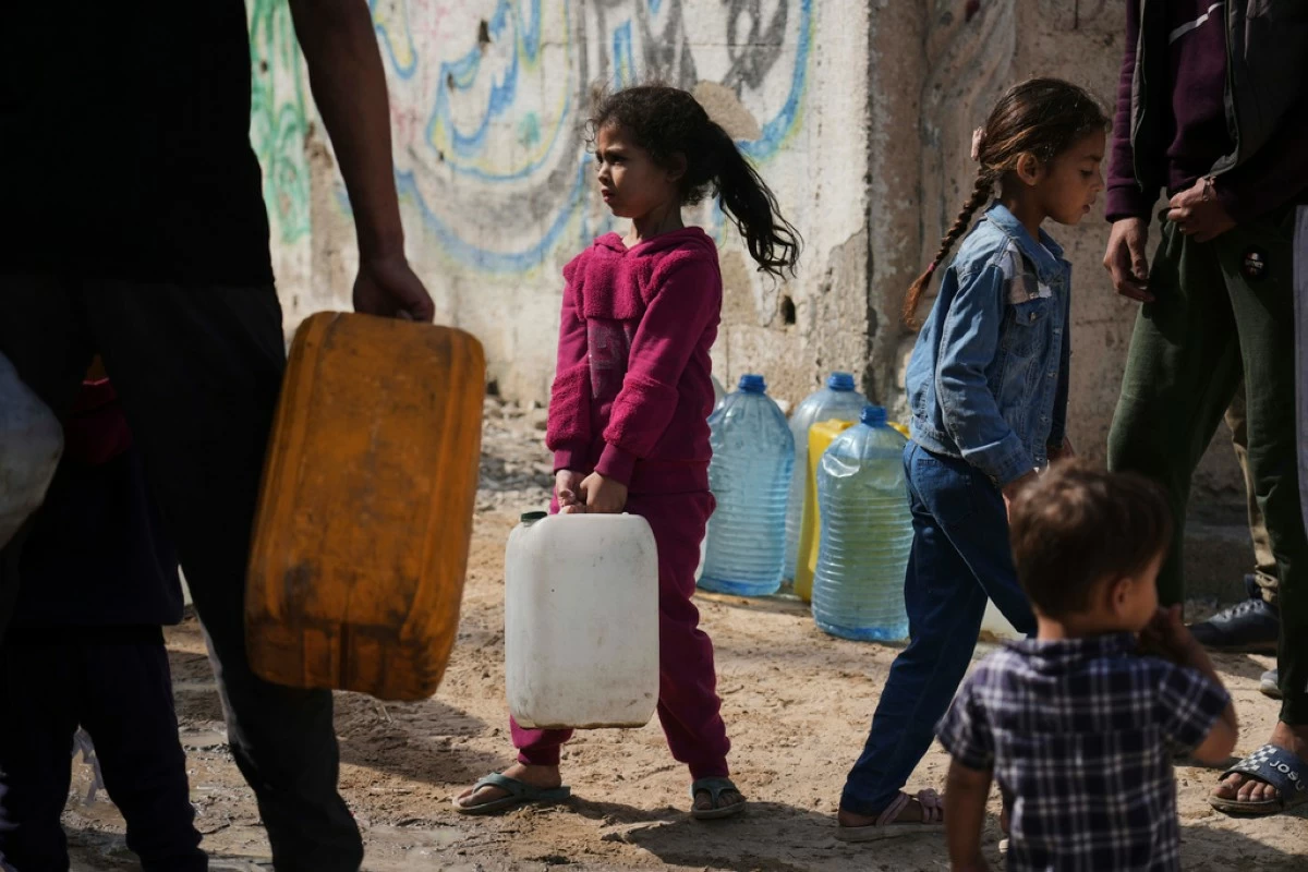 Palestinians collect water in jerrycans at a distribution point west of Gaza City, Sunday, May 11, 2025. (AP Photo/Jehad Alshrafi)