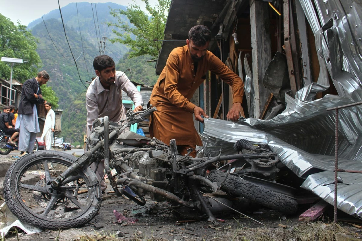 Local residents remove a burnt motorbike from near their shops damaged by Indian shelling, at the main bazaar, a day after the ceasefire between India and Pakistan was announced, near Jura, on the Line of Control, in Neelum Valley, a district of Pakistan's administered Kashmir, Sunday, May 11, 2025. (AP Photo/Ishfaq Hussain)