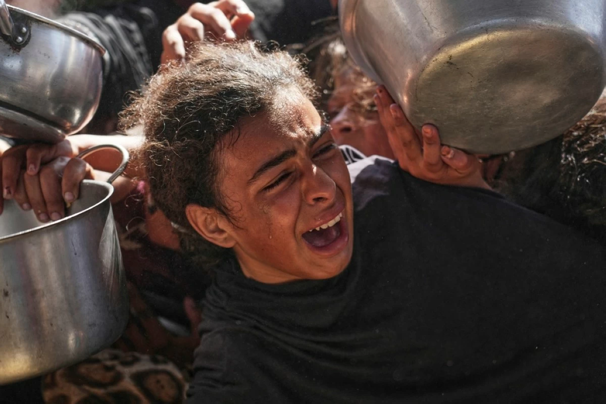 A Palestinian girl struggles to obtain donated food at a community kitchen in Khan Younis, in the southern Gaza Strip, Friday, May 9, 2025. (AP Photo/Abdel Kareem Hana)