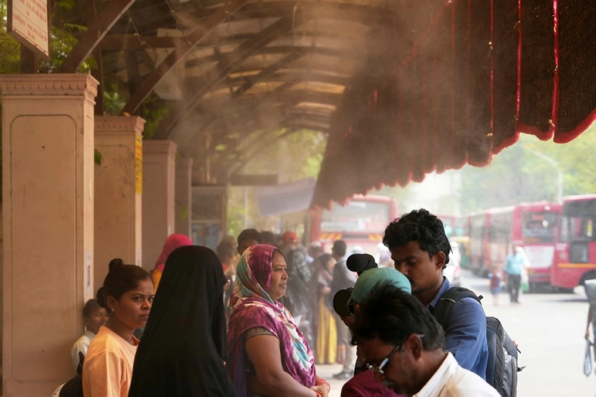 People wait for a bus at a cool bus stop in Ahmedabad, India, Wednesday, April 2, 2025. (AP Photo/Ajit Solanki)