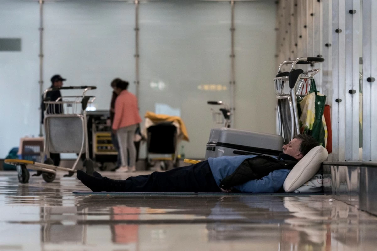 A person sleeps on the floor of Terminal 4 at Adolfo Suárez-Madrid Barajas Airport in Madrid, Spain, Monday, May 12, 2025. (Diego Radames/Europa Press via AP)