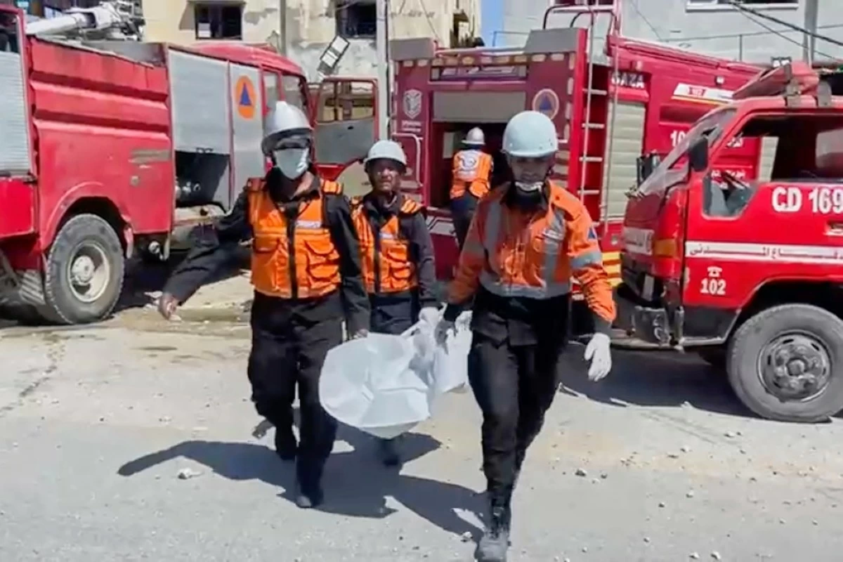 In this frame grab from a video released by Gaza Civil Defense, workers collect human remains after an Israeli strike on a home in Khan Younis killed nine of a doctor's ten children while she was at work, according to Ahmad al-Farra, head of the pediatric department at Nasser Hospital, in Khan Younis, Gaza Strip, Saturday, May 24, 2025. (Gaza Civil Defense via AP)