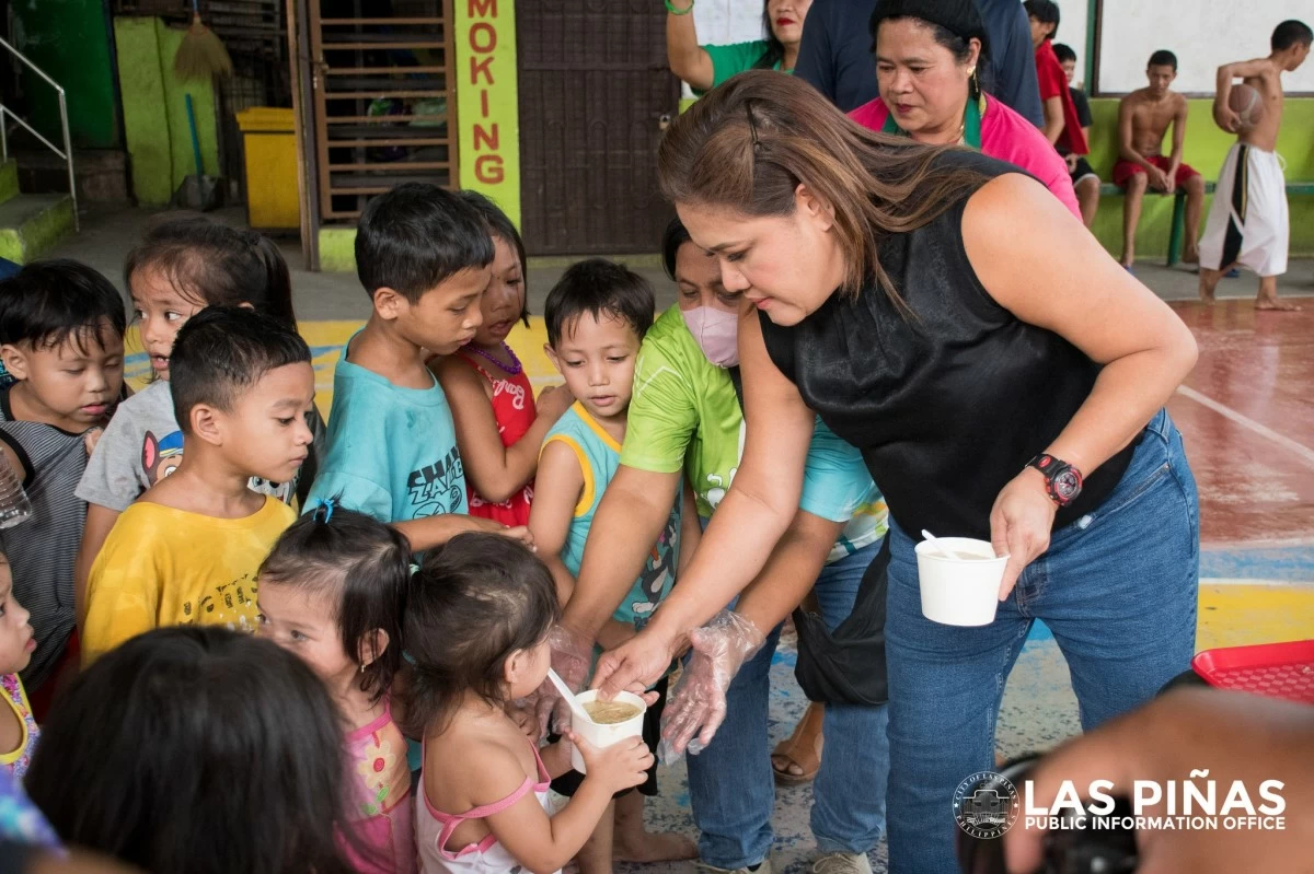 Las Pinas' newly-elected Mayor, April Aguilar, with children receiving arroz caldo meal. (Photo from Las Pinas PIO)
