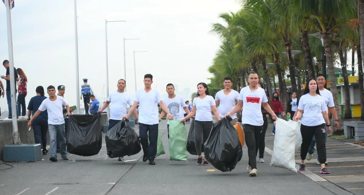 Employees carry sacks of collected waste during a coastal cleanup activity, underscoring their active role in advancing environmental protection through the company’s coastal cleanup initiative.