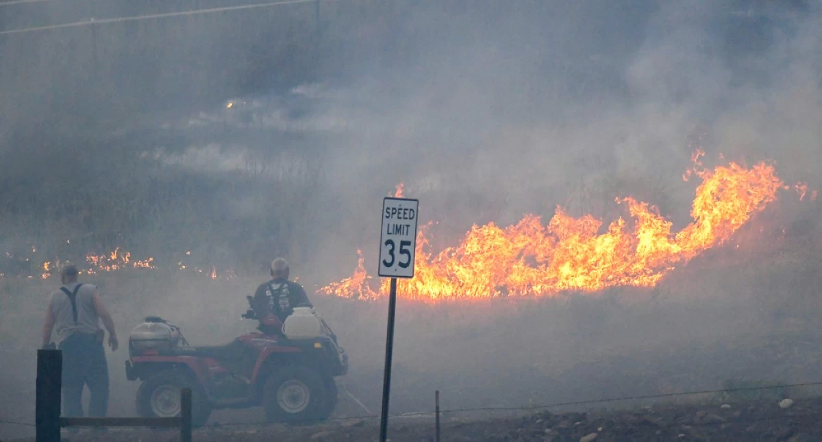 People watch as fire burns along Hatwai Road Saturday, May 31, 2025, in north Lewiston, Idaho. (August Frank/Lewiston Tribune via AP)