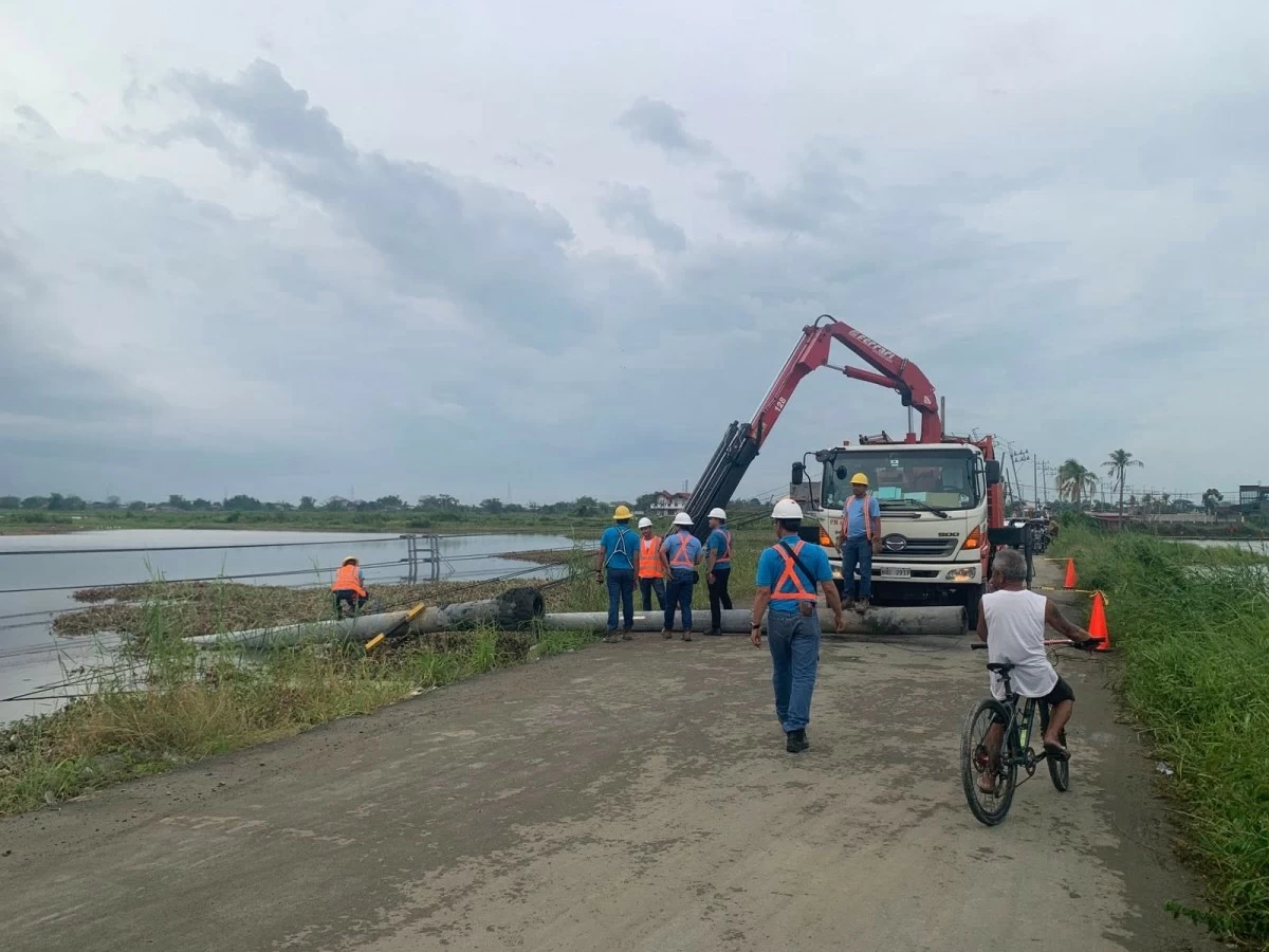 Meralco linemen reinstall several electric posts that collapsed in Barangay Bulusan, Calumpit, Bulacan, at the height of strong winds and heavy downpour on Friday afternoon, June 6, 2025. (Photo from the official Facebook page of Mayor Lem Faustino)