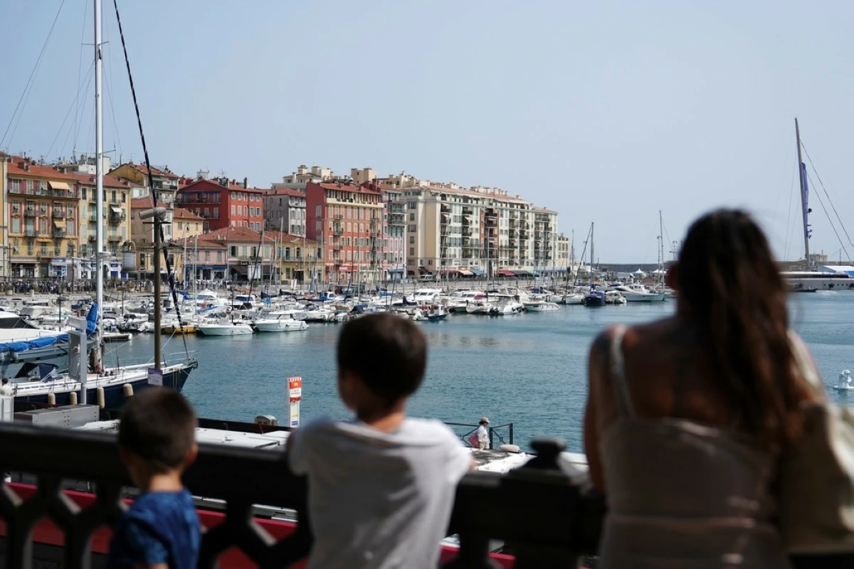 A family looks out at the boats on the water at Port Lympia where the upcoming U.N. Ocean Conference will take place on Sunday, June 8, 2025, in Nice, France. (AP Photo/Annika Hammerschlag)