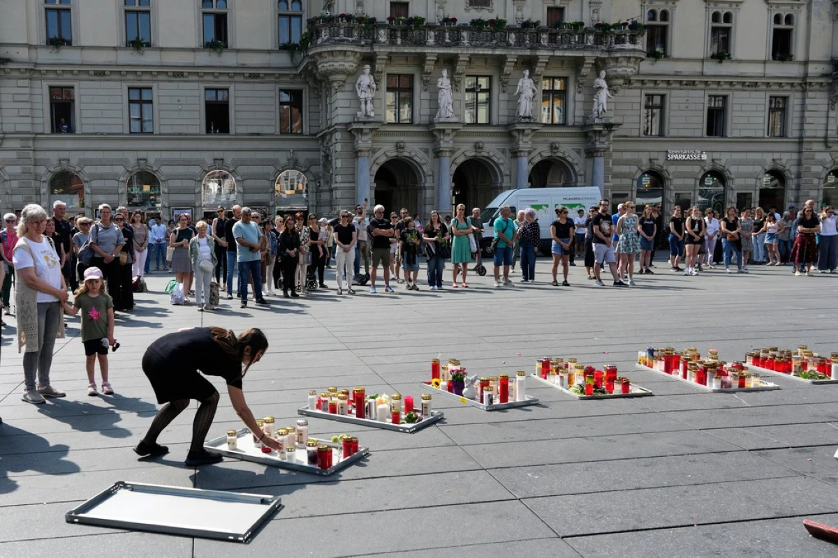People pay a moment of silence on the main square after a former student opened fire the day before at a school fatally wounding several people and injuring many others before taking his own life, Graz, Austria, Wednesday, June 11, 2025. (AP Photo/Darko Bandic)