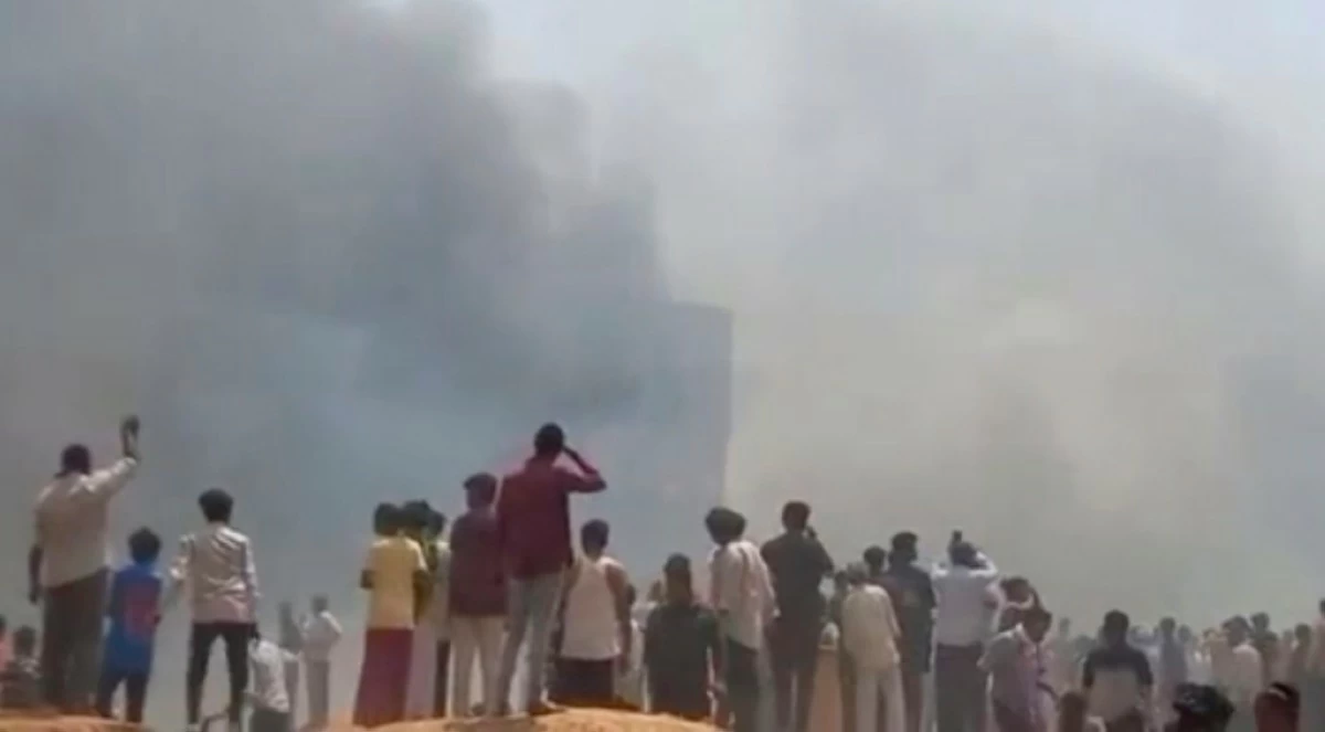 People watch smoke rising after an airplane crashed in Ahmedabad, Gujarat state, India, Thursday, June 12, 2025. (Mohan Nakum via AP)