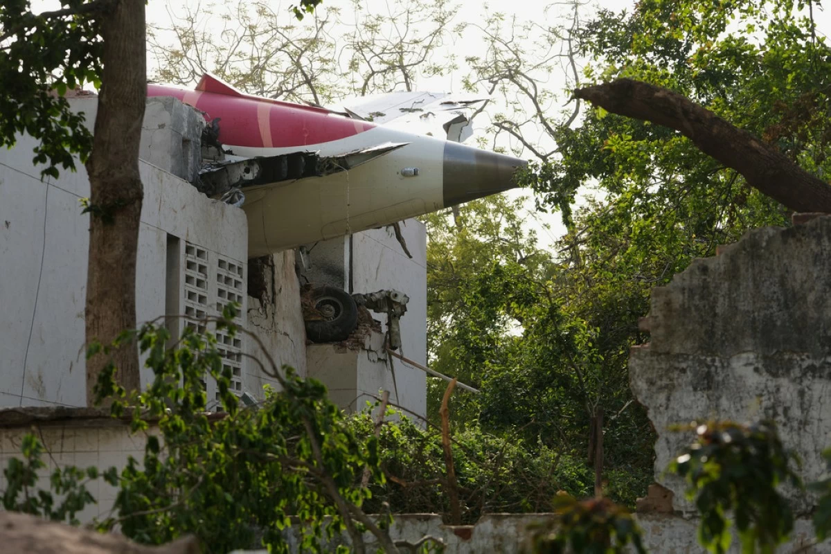 The tail of the airplane is seen stuck in a building at the site of an airplane that crashed in India's northwestern city of Ahmedabad in Gujarat state, Thursday, June 12, 2025. (AP Photo/Ajit Solanki)