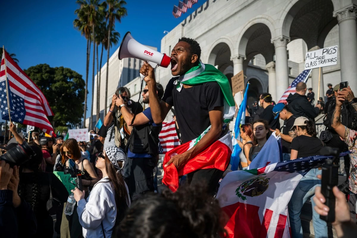 A man shouts into a megaphone outside City Hall during protests over federal immigration enforcement raids on Wednesday, June 11, 2025, in Los Angeles. (AP Photo/Ethan Swope)