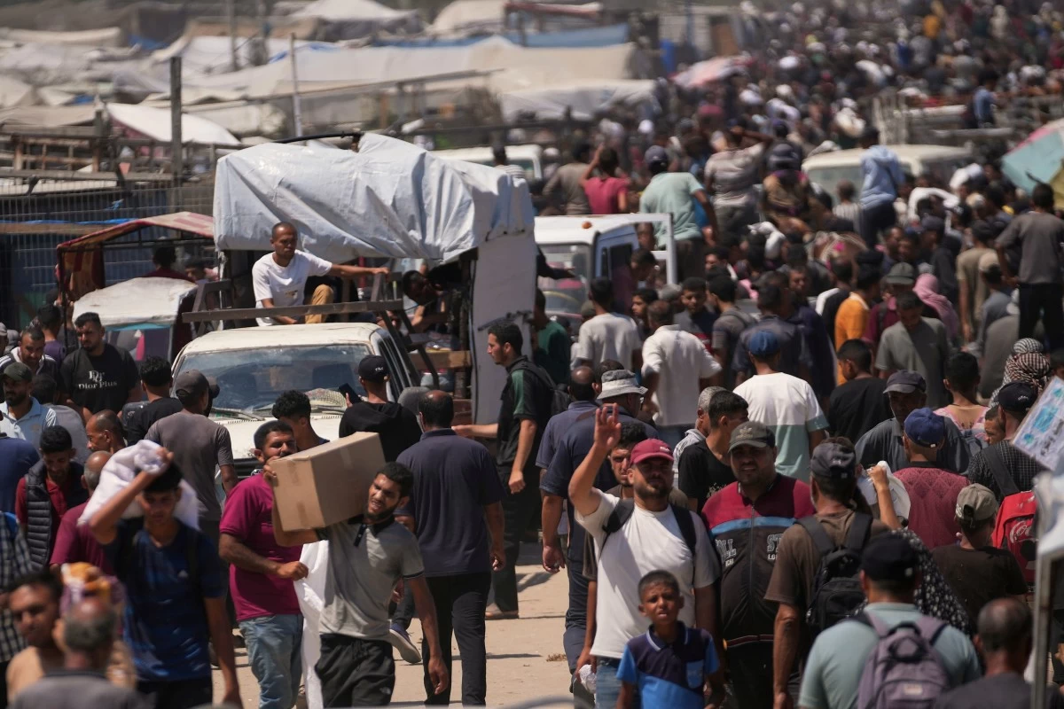 Palestinians carry bags containing food and humanitarian aid packages delivered by the Gaza Humanitarian Foundation, a U.S.-backed organization, in Rafah, southern Gaza Strip, Sunday, June 15, 2025. (AP Photo/Abdel Kareem Hana)