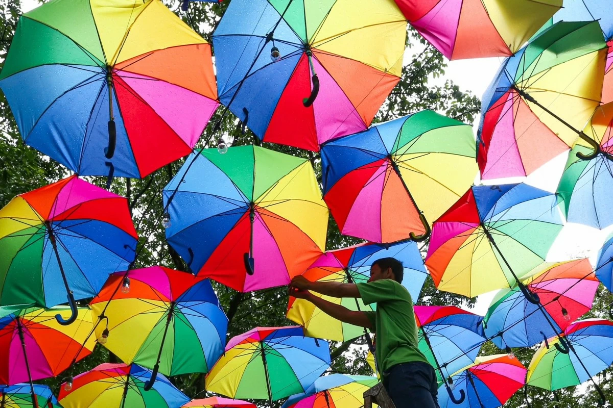 Quezon City Memorial Circle personnel install colorful umbrellas at the elevated garden on Tuesday, June 17, 2025, as part of the city’s Pride Month celebration. (Santi San Juan)