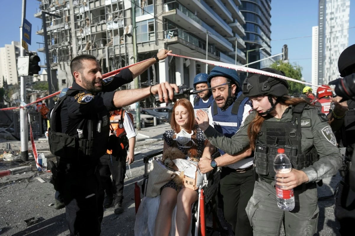 A woman is evacuated from the site of a direct hit from an Iranian missile strike in Ramat Gan, Israel, Thursday, June 19, 2025. (AP Photo/Oded Balilty)