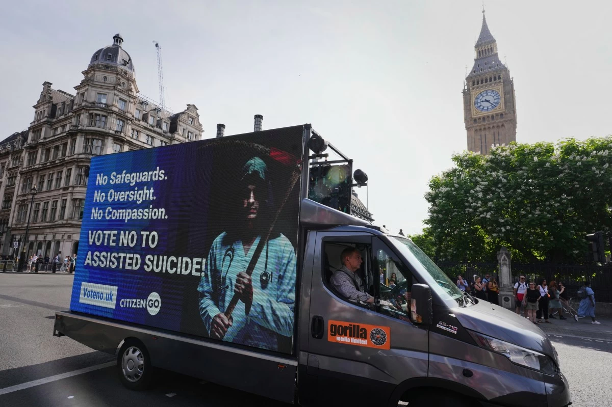 A van displaying a sign passes Big Ben as demonstrators both for and against assisted dying hold banners outside Parliament in London, Friday, June 20, 2025, as British lawmakers are set to vote Friday on whether to back a bill to help terminally ill adults end their lives in England and Wales. (AP Photo/Kirsty Wigglesworth)