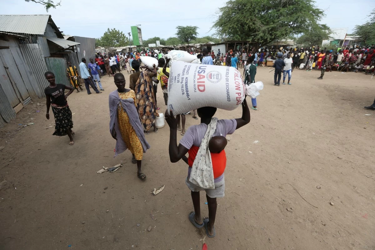 Refugees carry food at a distribution center run by the World Food Programme (WFP) at Kakuma Refugee Camp in Turkana, Kenya Tuesday, June 3, 2025. (AP Photo/Andrew Kasuku)