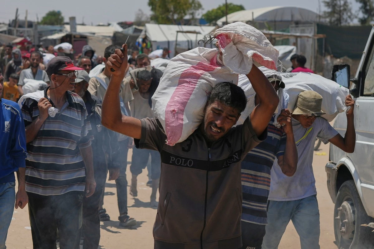 A Palestinian carries a bag containing food and humanitarian aid delivered by the Gaza Humanitarian Foundation, a U.S.-backed organization, in Rafah, southern Gaza Strip, Wednesday, June 11, 2025. (AP Photo/Abdel Kareem Hana)