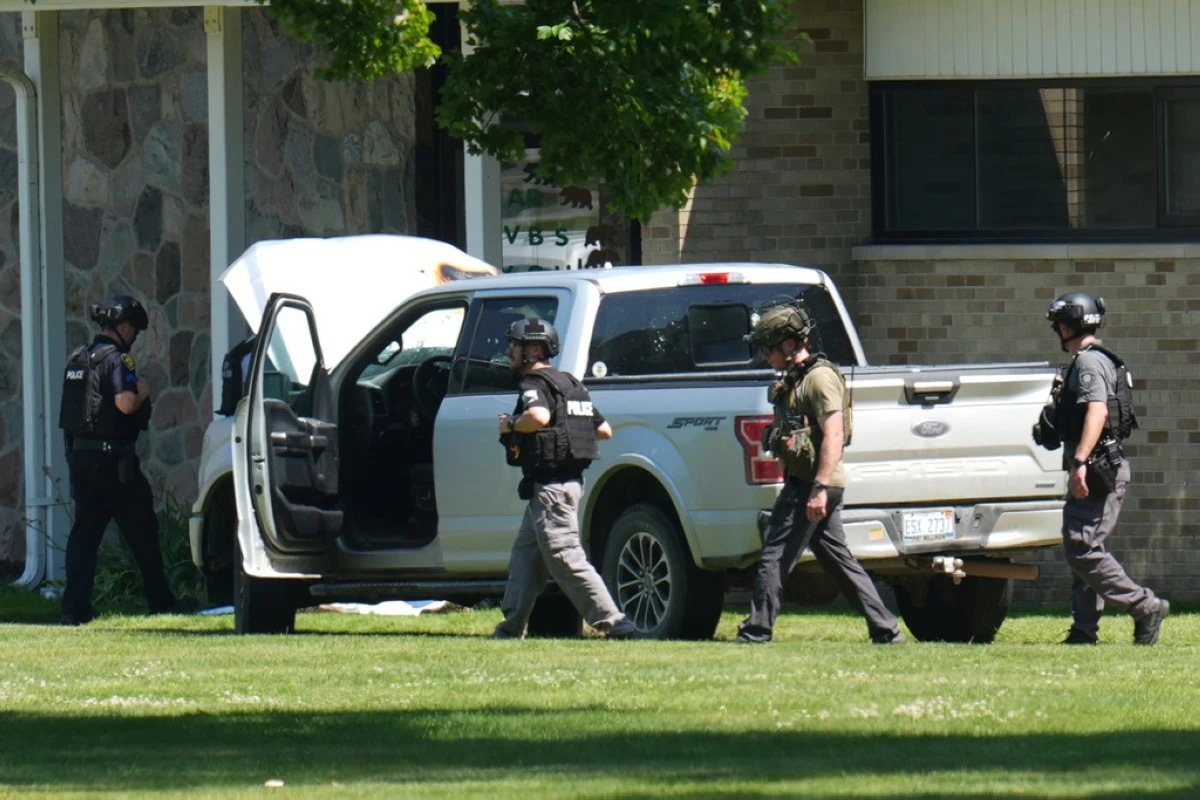 Police walk by an idle vehicle near CrossPointe Community Church in Wayne, Mich., Sunday, June 23, 2025. (AP Photo/Paul Sancya)