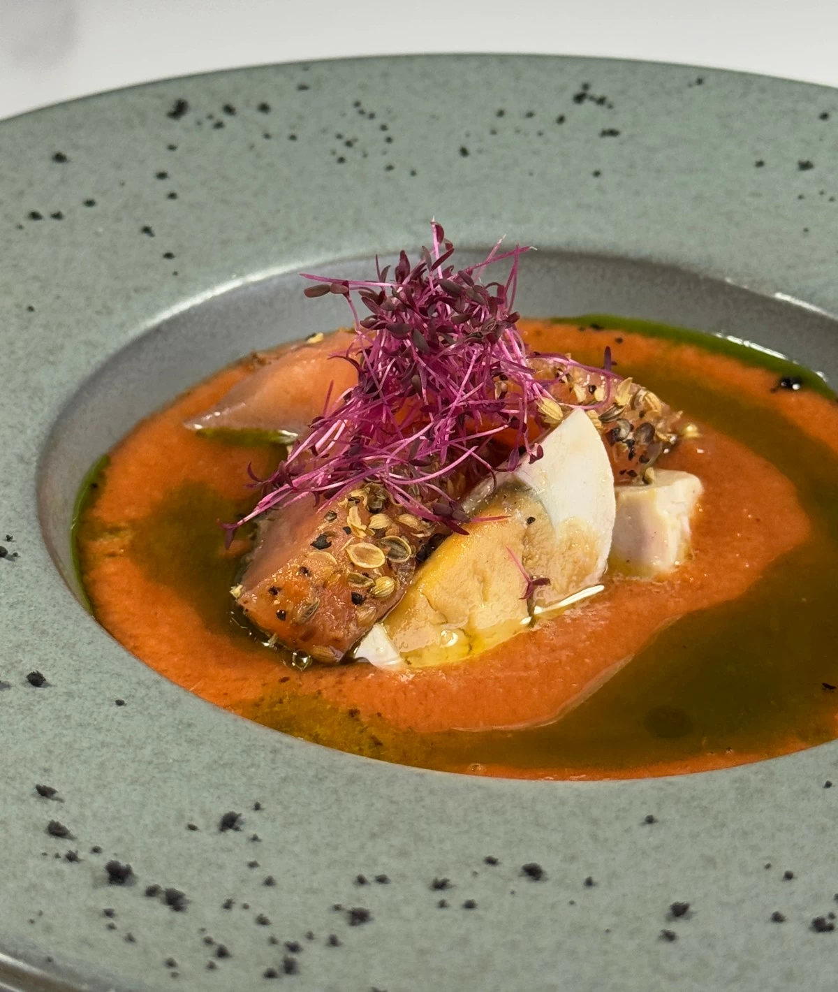 COOL CONTRAST Ensalada opens the meal with chilled tomato soup poured over salmon pastrami, salted egg, and pako, offering a refreshing balance of brine, creaminess, and crisp local greens