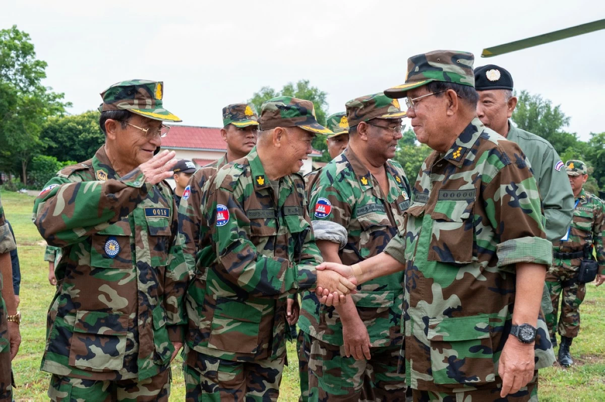In this photo released by Agence Kampuchea Press (AKP), Cambodian Senate President Hun Sen, right, greets with his top general officers during his visit to Oddar Meanchey province, near Cambodia-Thailand border of northern province of Cambodia, Thursday, June 26, 2025. (AKP via AP)