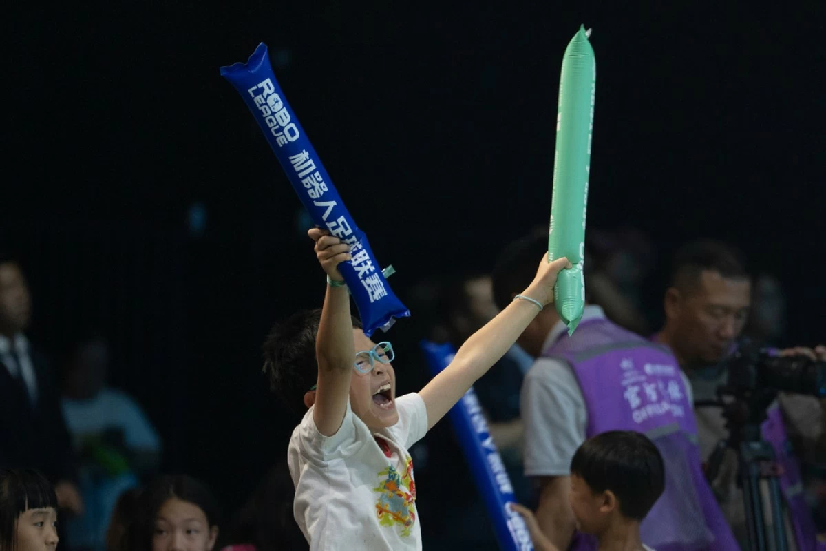 A child reacts as he watches the inaugural RoBoLeague robot soccer competition in Beijing, Saturday, June 28, 2025. (AP Photo/Ng Han Guan)