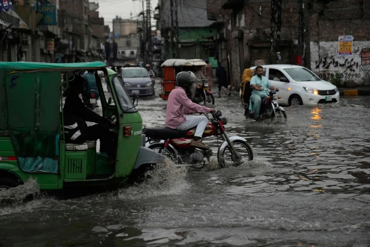 Motorists drive through a flooded road caused by heavy monsoon rains, in Lahore, Pakistan, Sunday, June 29, 2025. (AP Photo/K.M. Chaudary)
