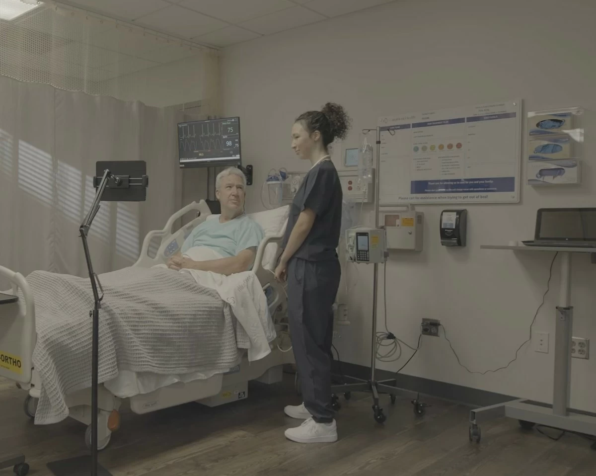 A hospital patient in the United States is introduced to his virtual sitter in the Philippines, who will help ensure his safety by monitoring his behavior and immediately alerting on-site care teams in the U.S. to any high-risk actions, such as attempts to get out of bed.