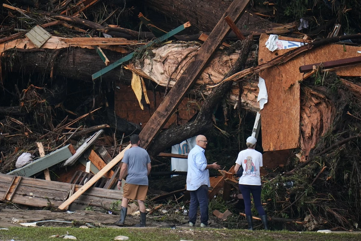 People look at debris on the banks of the Guadalupe River after a flash flood swept through the area Saturday, July 5, 2025, in Hunt, Texas. (AP Photo/Julio Cortez)