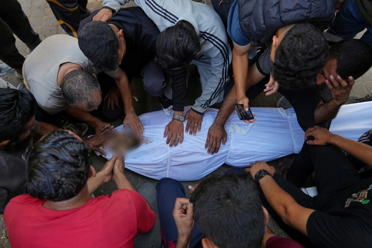 Relatives mourn over the body of Palestinian Bilal Abu Amsha, who was killed among others in Israeli strikes on the Gaza Strip, at Al-Shifa Hospital in Gaza City, Saturday, June 28, 2025. (AP Photo/Jehad Alshrafi)