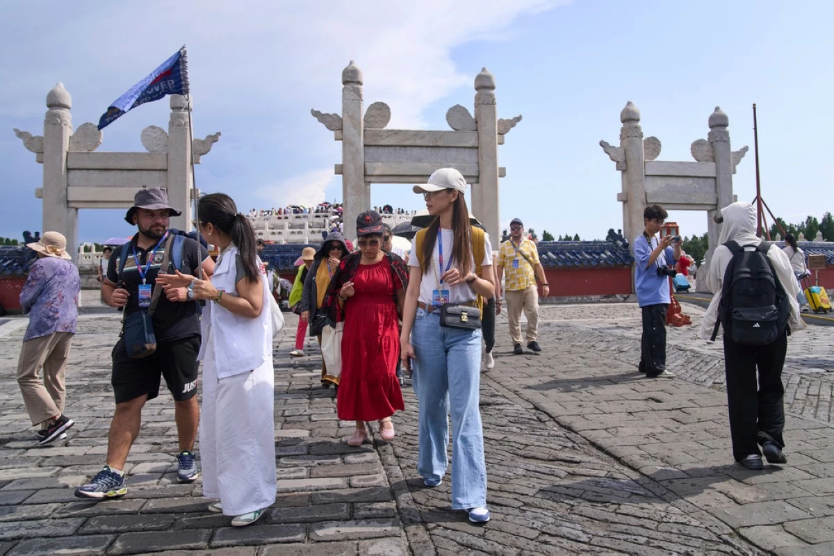 A tour guide chats with a tourist as they tour the Temple of Heaven, in Beijing on June 15, 2025. (AP Photo/Andy Wong)