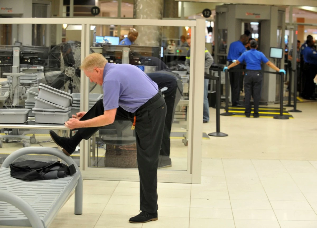 FILE - A traveler removes his shoes at Hartsfield-Jackson Atlanta International Airport on Wednesday, Jan. 15, 2014 in Atlanta.  (Kent D. Johnson/Atlanta Journal-Constitution via AP, File)