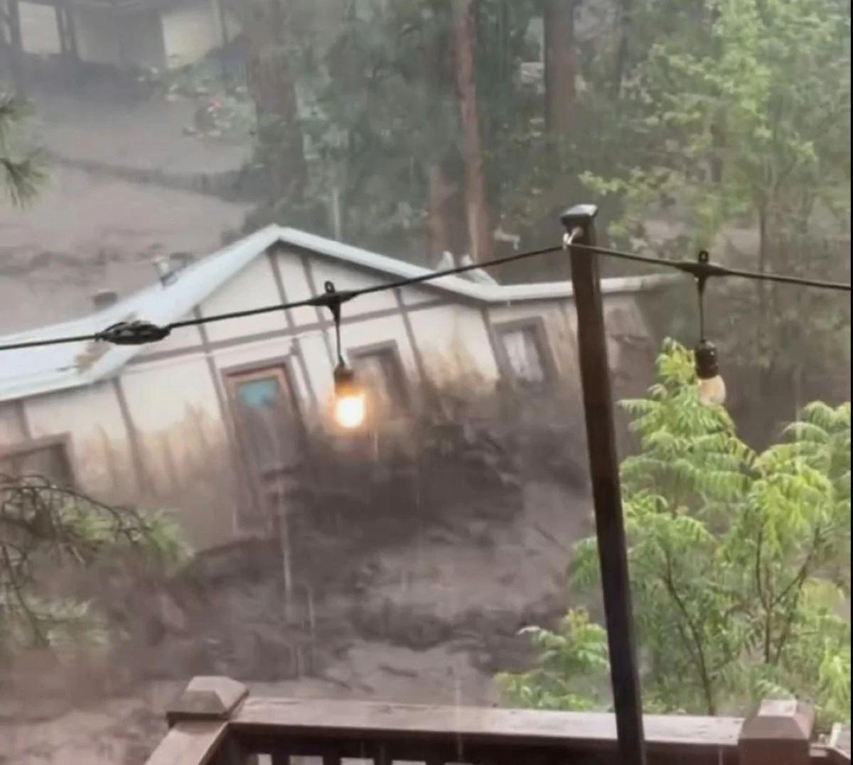 IN this image taken from video, a house is carried away by flash flooding behind a house in Ruidoso, New Mexico, Tuesday, July 8, 2025. (Kaitlyn Carpenter via AP)