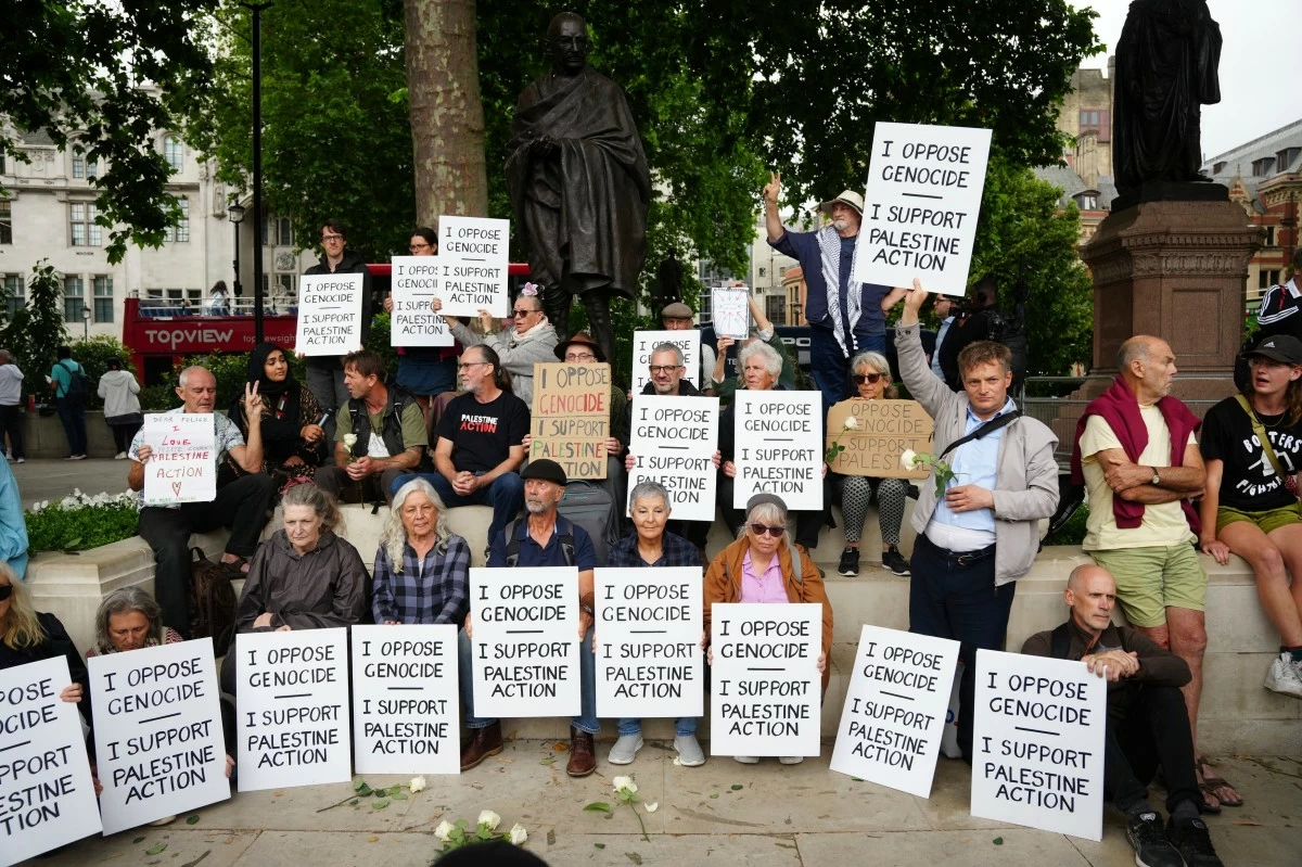 People take part in a protest in support of 'Palestine Action', organised by the Defend Our Juries group, in front of the Mahatma Gandhi statue in Parliament Square in London, England, Saturday, July 5, 2025. (Jeff Moore/PA via AP)