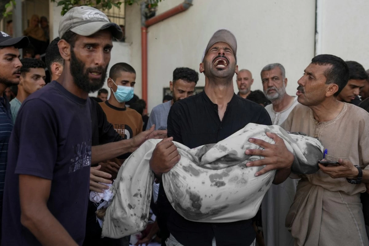 A Palestinian man carries the body of his child, who was killed in an Israeli military airstrike on Gaza, at Shifa Hospital in Gaza City, Saturday, July 12, 2025. (AP Photo/Jehad Alshrafi)
