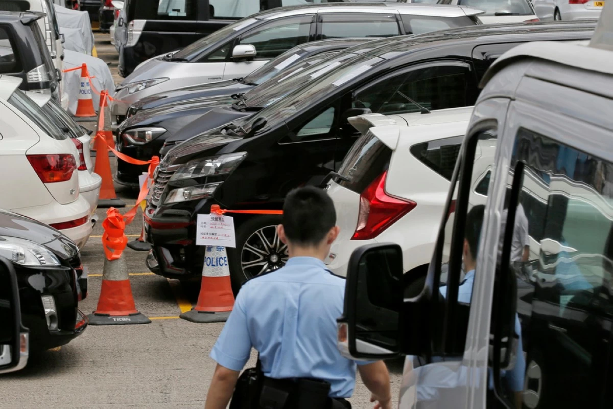 FILE - Impounded vehicles meant for Uber service, center, are parked behind a police cordon line at a police station in Hong Kong, Tuesday, May 23, 2017. (AP Photo/Kin Cheung, File)
