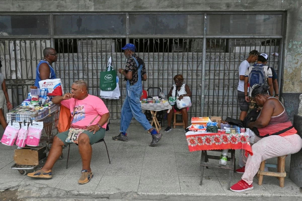 Street vendors wait for customers at the entrance of a state-owned establishment in Havana, Cuba, Tuesday, July 15, 2025. (AP Photo/Jorge Luis Baños)