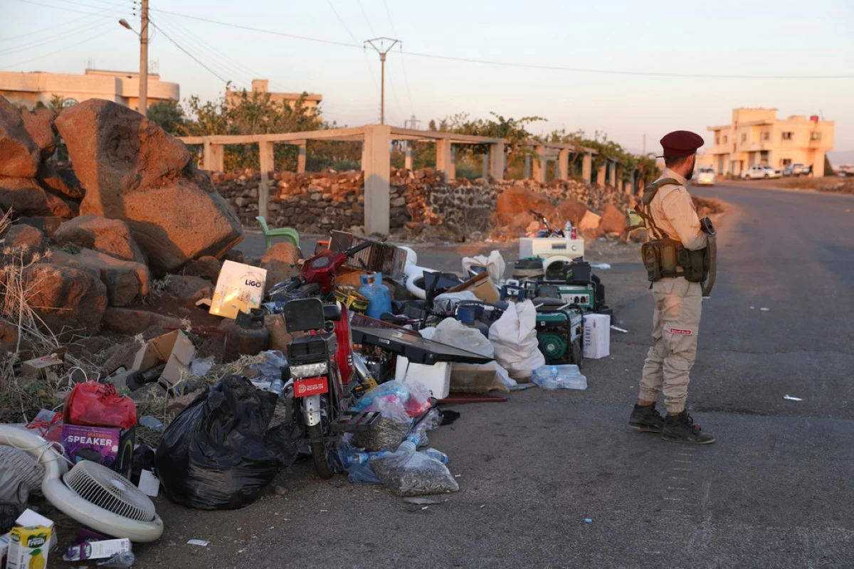 A military police unit soldier stands next of confiscate items stolen during clashes in Sweida city between government forces and Druze militias at a checkpoint in Mazraa village, southern Syria, Tuesday, July 15, 2025. (AP Photo/Omar Albam)
