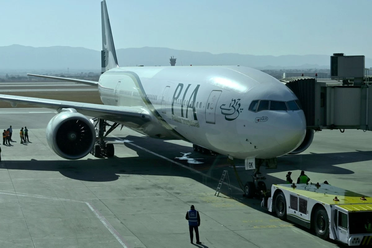 FILE -Ground staff work beside the state-run Pakistan International Airlines plane preparing to take-off for Paris after the airline resumes direct flights to Europe after EU lifted a four-year ban, at the Islamabad International Airport, in Islamabad, Pakistan, Jan. 10, 2025. (AP Photo), File)