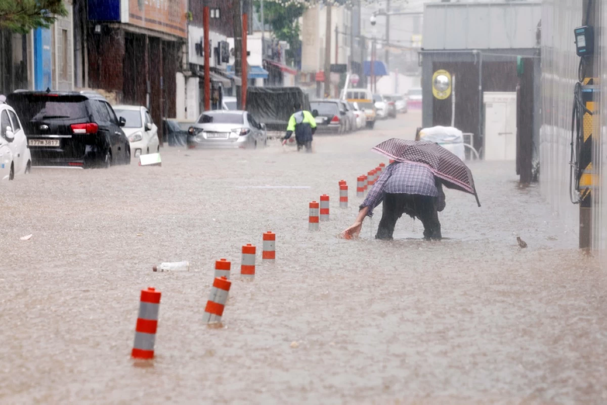 People wade through an inundated street due to heavy rain in Gwangju, South Korea, Thursday, July 17, 2025. (Jeong Da-eum/Yonhap via AP)
