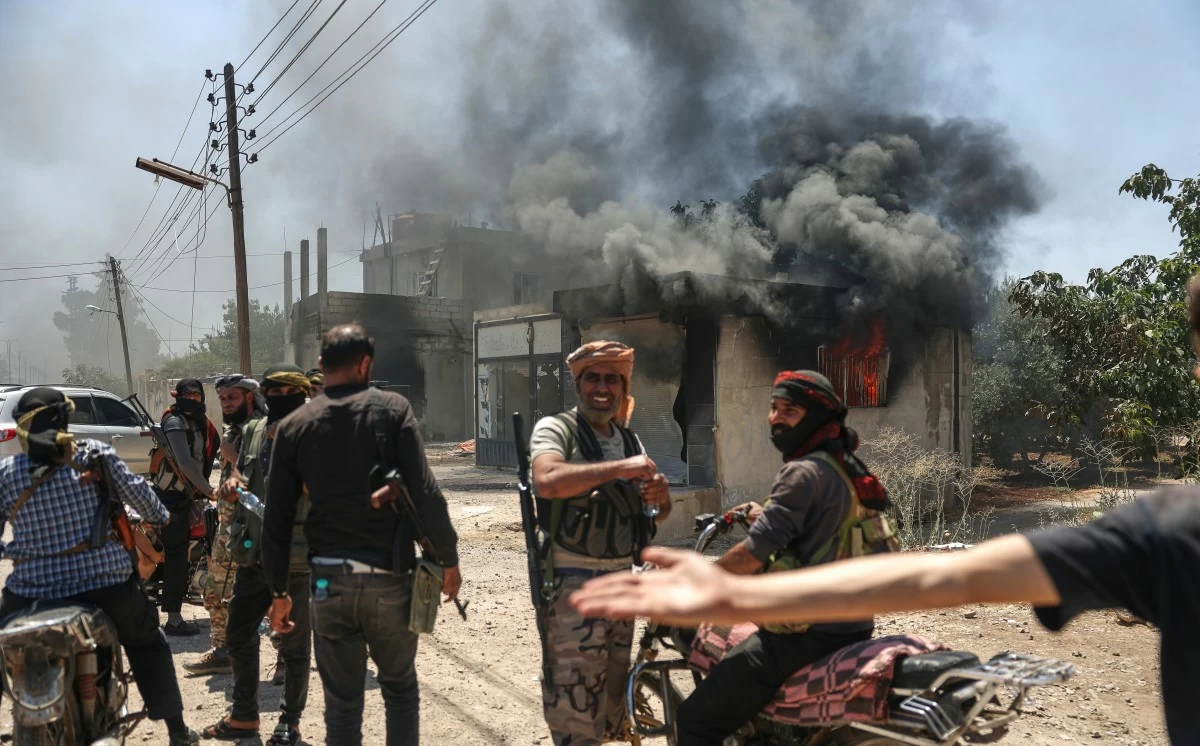 Bedouin fighters gather in front a burned shop at Mazraa village on the outskirts of Sweida city, during clashes between the Bedouin clans and Druze militias, southern Syria, Friday, July 18, 2025. (AP Photo/Ghaith Alsayed)

