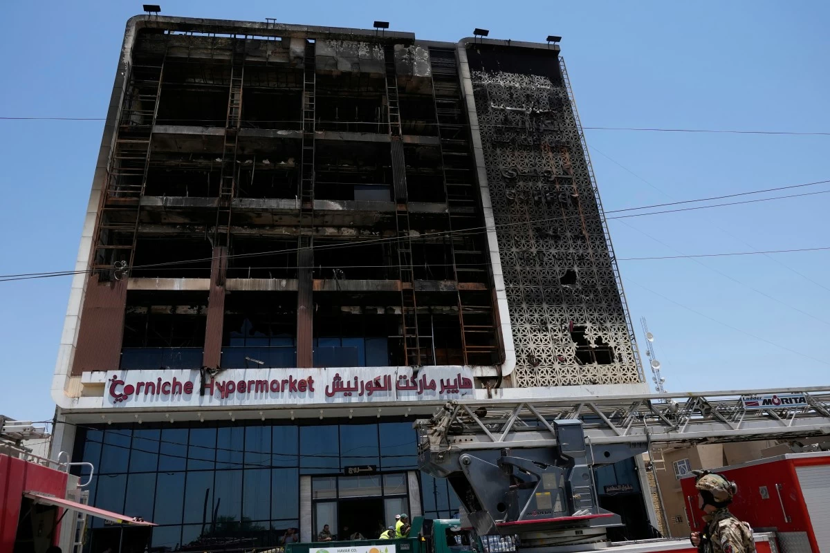Iraqi security forces gather in front of a burning hypermarket building in Kut, Iraq, Thursday, July 17, 2025. (AP Photo/Hadi Mizban)