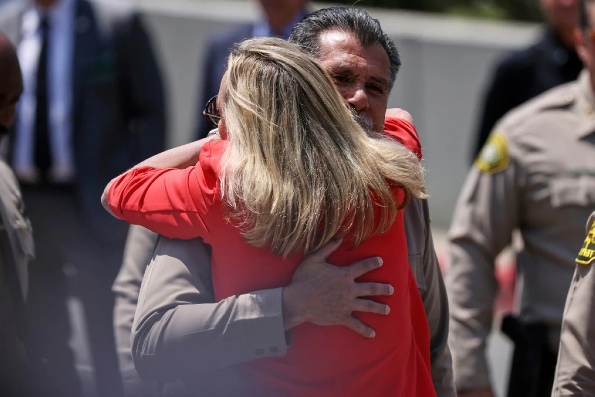 Los Angeles County Sheriff Robert Luna gets a hug from Supervisor Kathryn Barger as he arrives for a press conference after three members of the department were killed in an explosion at a training facility on Friday, July 18, 2025, in Los Angeles. (AP Photo/Etienne Laurent)