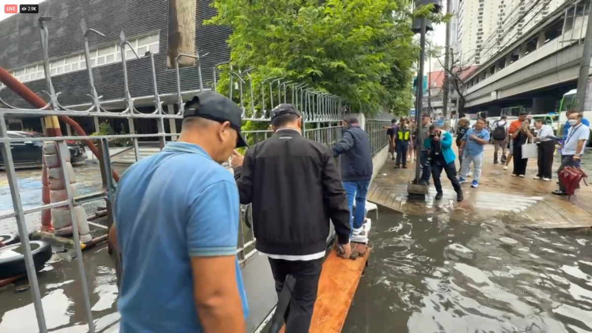 Mayor Isko Moreno, accompanied by his team, crosses a wooden plank laid over a flooded section of Taft Avenue during an on-site inspection on Monday, July 21.