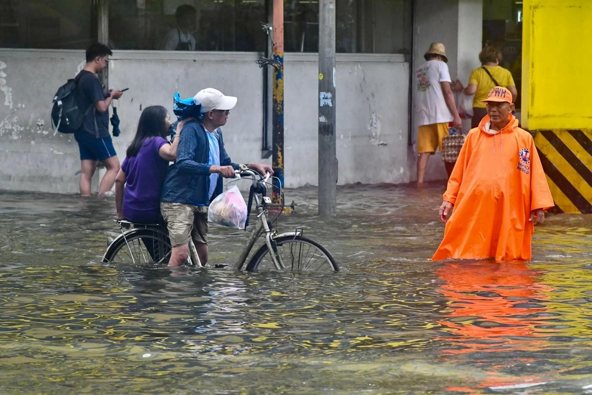 Motorists and commuters wade through floodwaters along España Boulevard in Manila following heavy rains on Tuesday, July 22, 2025.