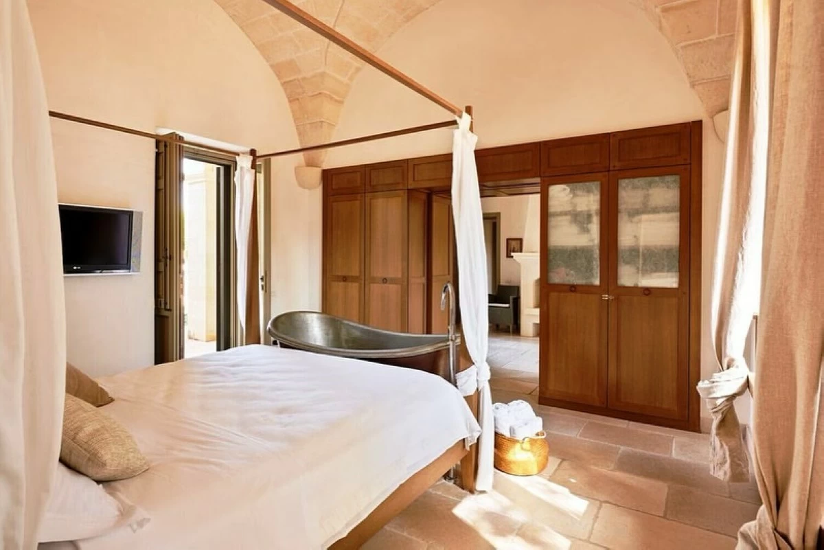 The master bedroom features a canopy bed and a freestanding bathtub. 